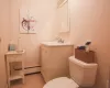 Bathroom featuring a baseboard heating unit, tile flooring, vanity, and toilet