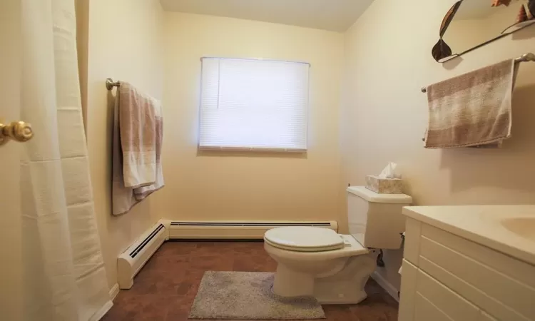 Bathroom with tile floors, a baseboard heating unit, toilet, and vanity