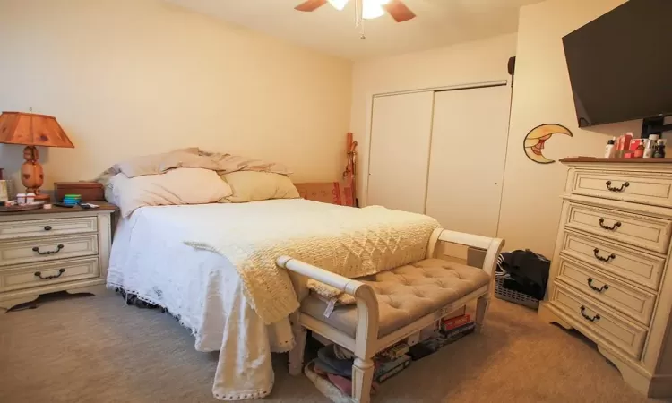 Bedroom featuring a closet, dark colored carpet, and ceiling fan