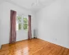 Empty room featuring ceiling fan, radiator, and light hardwood / wood-style flooring