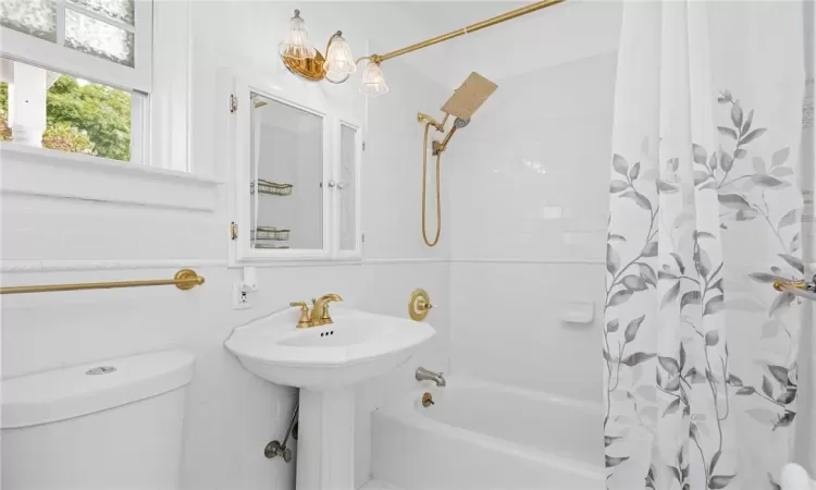 Full bathroom featuring sink, shower / tub combo, tile walls, and toilet