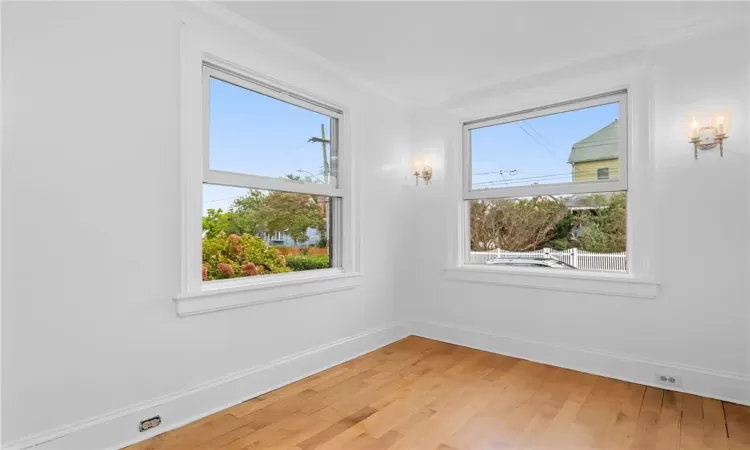 Unfurnished room with hardwood / wood-style flooring, ornamental molding, and a healthy amount of sunlight