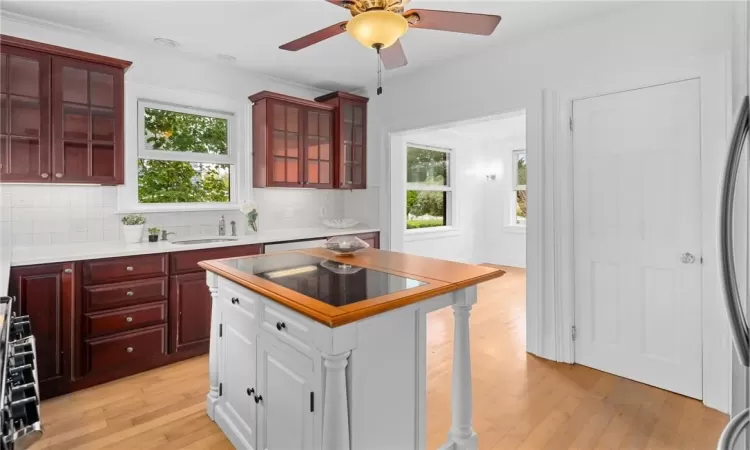 Kitchen with light hardwood / wood-style flooring, backsplash, sink, and crown molding