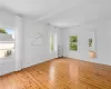 Spare room featuring beamed ceiling, plenty of natural light, light hardwood / wood-style floors, and radiator heating unit