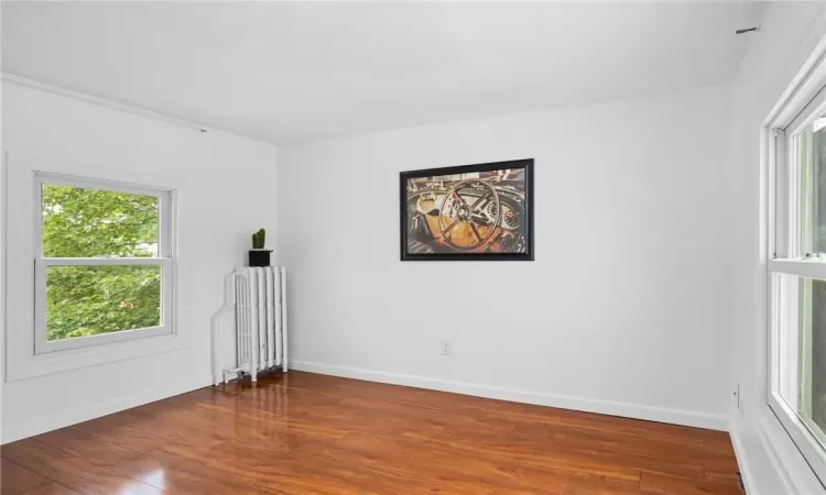 Spare room featuring radiator heating unit and hardwood / wood-style flooring