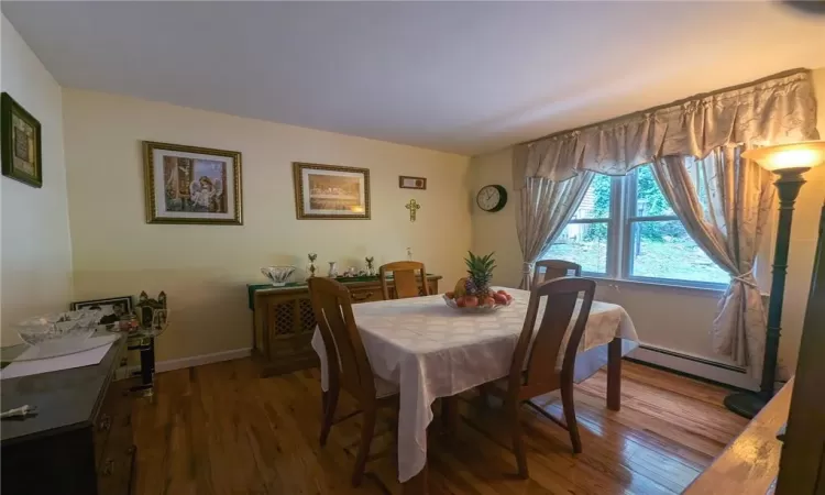 Dining area featuring a baseboard heating unit and dark wood-type flooring