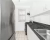 Kitchen featuring wall chimney range hood, decorative backsplash, gas range oven, white cabinetry, and stainless steel fridge