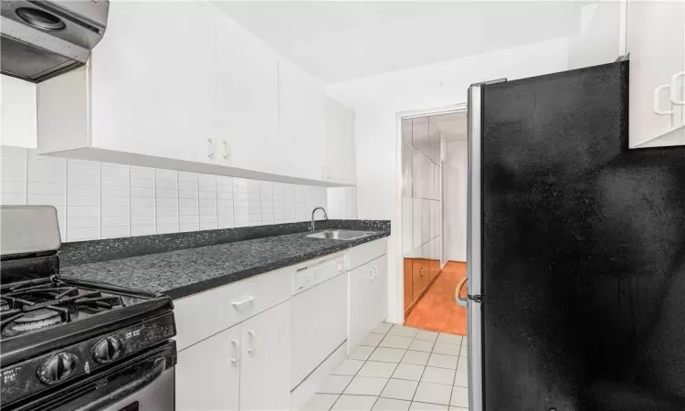 Kitchen featuring black range, light hardwood / wood-style flooring, decorative backsplash, range hood, and refrigerator