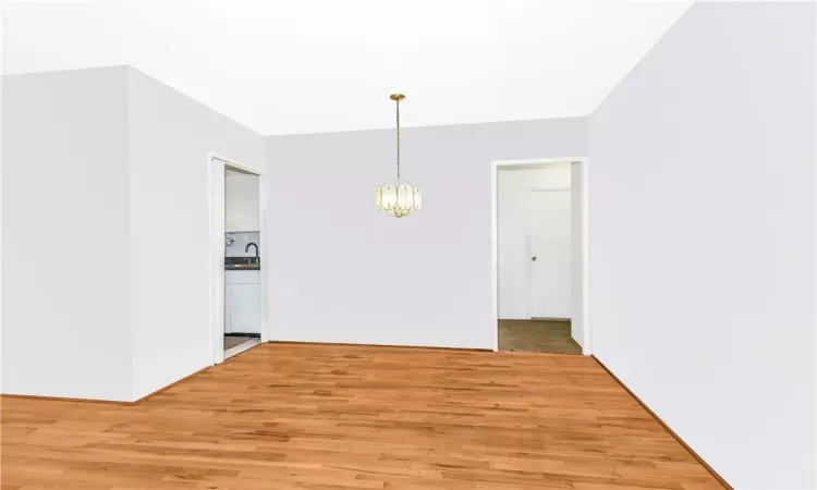 Unfurnished dining area with light hardwood / wood-style floors, sink, and a notable chandelier