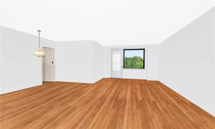 Spare room featuring light wood-type flooring and a chandelier