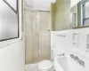 Bathroom featuring tile walls, a shower with shower door, sink, and toilet