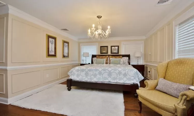 Bedroom featuring dark hardwood / wood-style floors, a notable chandelier, and ornamental molding