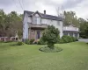 View of front of property featuring central AC, a garage, and a front lawn