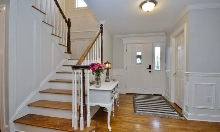 Foyer with plenty of natural light, ornamental molding, and light hardwood / wood-style flooring