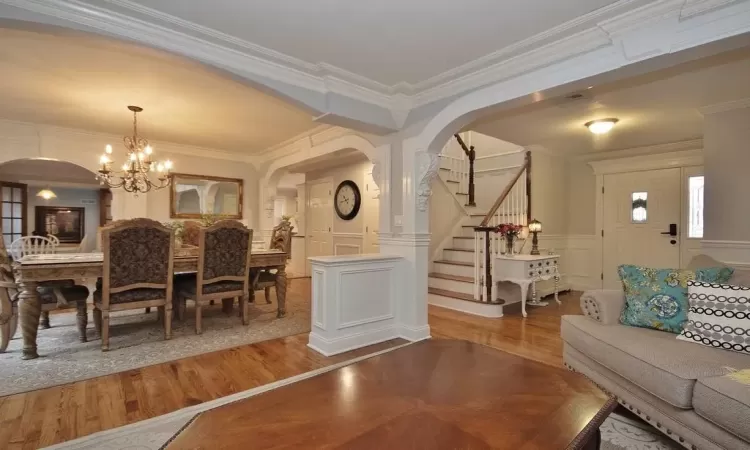 Living room featuring ornamental molding, hardwood / wood-style floors, a chandelier, and ornate columns