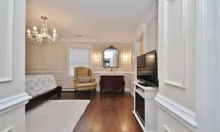 Bedroom featuring crown molding, dark hardwood / wood-style flooring, baseboard heating, and a notable chandelier