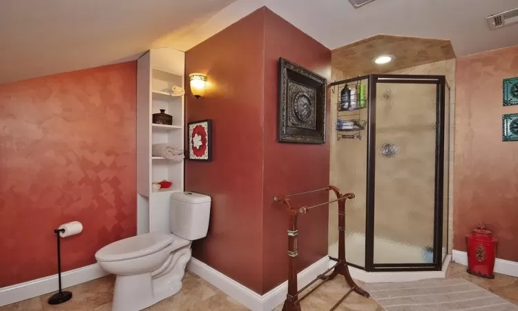 Bathroom featuring built in shelves, walk in shower, toilet, and tile patterned floors