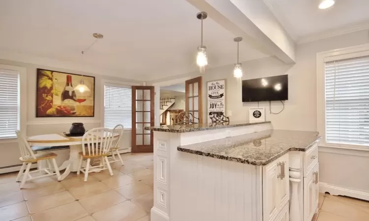 Kitchen featuring light tile patterned floors, crown molding, stone counters, kitchen peninsula, and pendant lighting