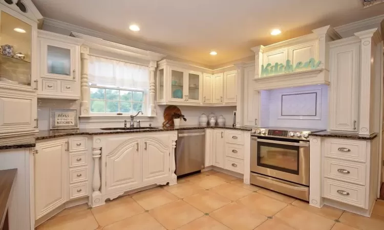 Kitchen featuring stainless steel appliances, backsplash, and white cabinetry