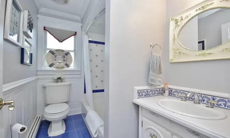 Full bathroom featuring vanity, toilet, ornamental molding, shower / bath combo, and a baseboard heating unit