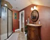 Bathroom featuring vanity, lofted ceiling, an enclosed shower, and tile patterned flooring