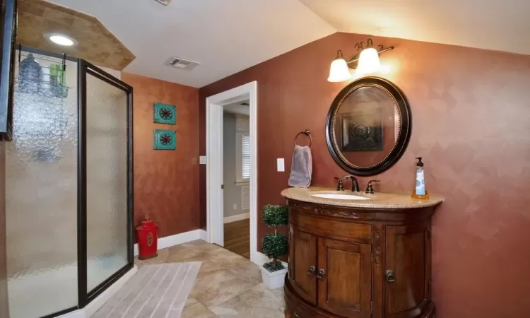 Bathroom featuring vanity, lofted ceiling, an enclosed shower, and tile patterned flooring