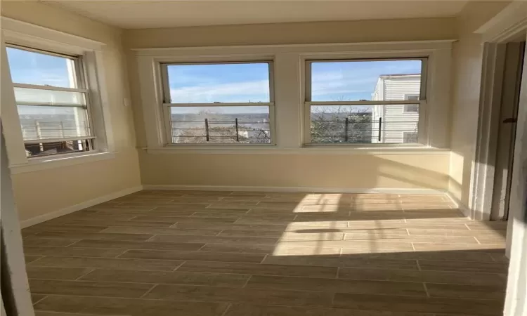 Empty room with a wealth of natural light, crown molding, and dark hardwood / wood-style flooring