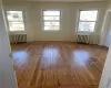 Unfurnished room featuring a wealth of natural light, hardwood / wood-style flooring, and radiator heating unit