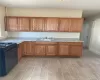 Kitchen with light stone counters, light hardwood / wood-style floors, sink, and black gas range oven