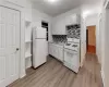 Kitchen with white cabinets, backsplash, light hardwood / wood-style flooring, white appliances, and ornamental molding