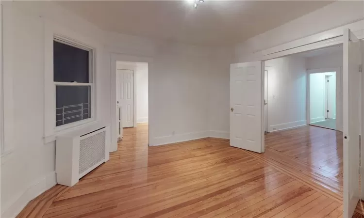 Unfurnished room featuring radiator and light wood-type flooring