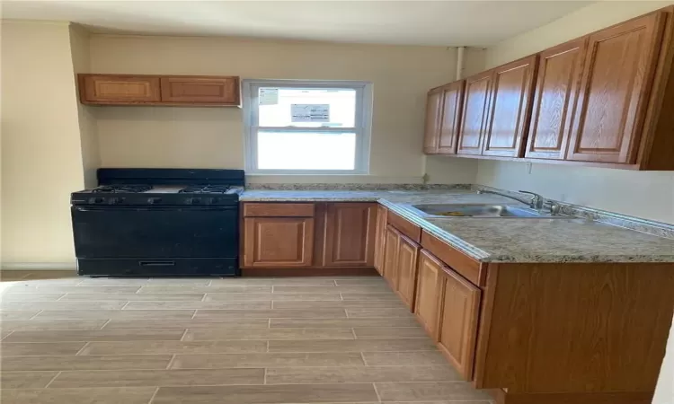 Kitchen with light wood-type flooring, gas stove, and sink