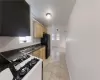 Kitchen with white gas range, sink, light brown cabinets, black refrigerator, and light tile patterned flooring