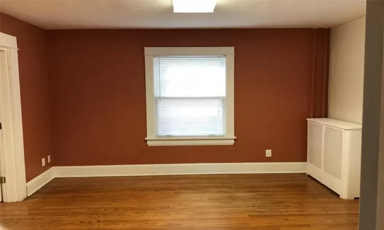 Unfurnished room featuring hardwood / wood-style flooring and radiator heating unit