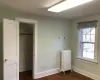 Unfurnished bedroom featuring a closet, radiator, and dark wood-type flooring