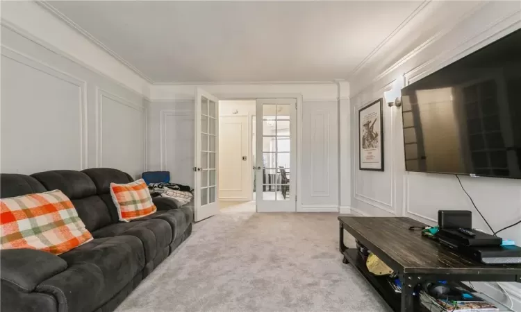 Carpeted living room featuring crown molding and french doors