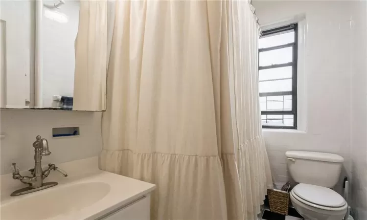 Bathroom with tile walls, toilet, and vanity