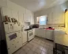 Apt1 Kitchen featuring white cabinetry, white appliances, light tile patterned floors, sink, and washer / dryer