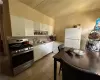 Apt 2 Kitchen with stainless steel range with gas stovetop, dark tile patterned floors, decorative backsplash, white refrigerator, and white cabinets