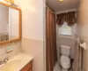 Bathroom with vanity, walk in shower, tile patterned flooring, tile walls, and toilet