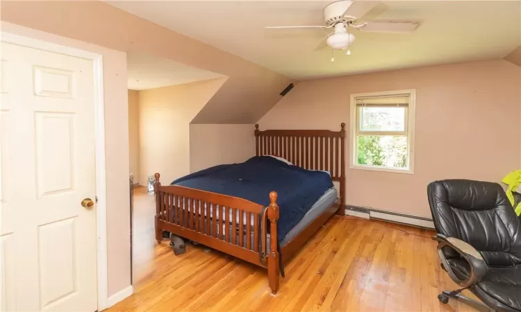 Bedroom featuring lofted ceiling, light hardwood / wood-style flooring, baseboard heating, and ceiling fan