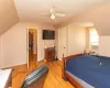 Bedroom featuring light wood-type flooring, vaulted ceiling, radiator heating unit, and ceiling fan