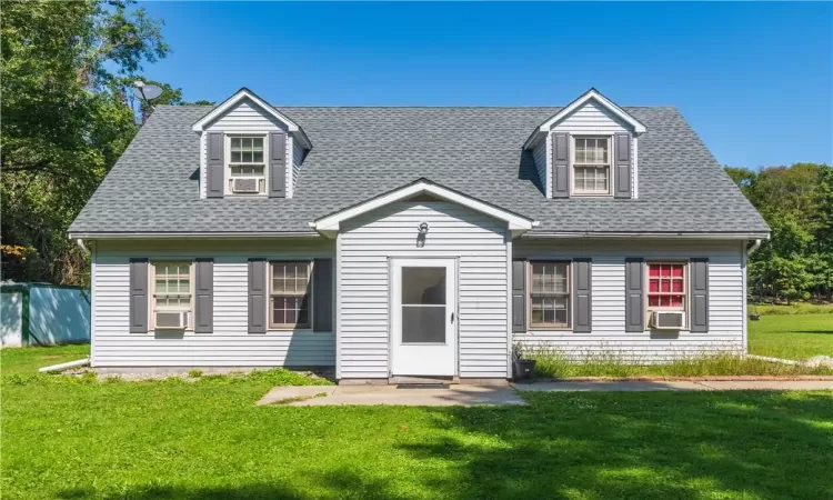 New england style home featuring cooling unit and a front lawn