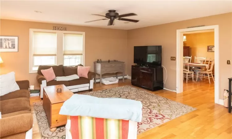 Living room with ceiling fan and hardwood / wood-style flooring