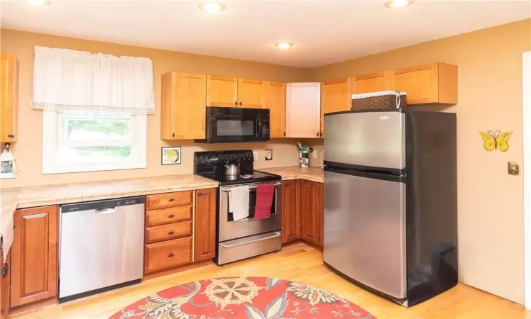 Kitchen with appliances with stainless steel finishes and light hardwood / wood-style flooring