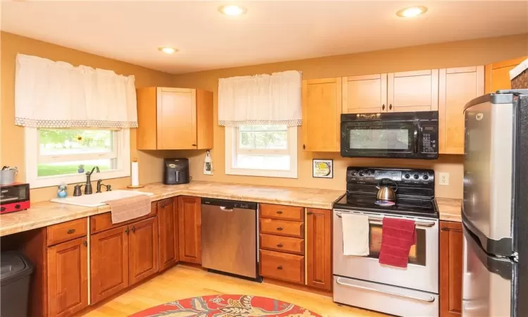 Kitchen featuring a wealth of natural light, light wood-type flooring, sink, and appliances with stainless steel finishes