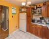 Kitchen featuring light wood-type flooring, a chandelier, backsplash, light stone counters, and white refrigerator