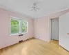 Unfurnished room featuring radiator heating unit, light wood-type flooring, crown molding, and ceiling fan