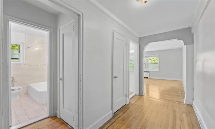 Hallway with ornamental molding, hardwood / wood-style floors, and radiator heating unit