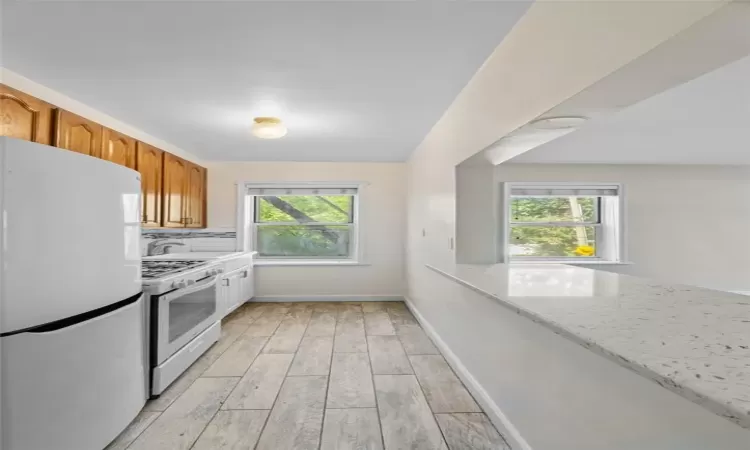 Kitchen with white appliances, light stone countertops, and light hardwood / wood-style floors